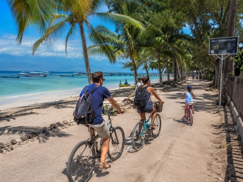 Family cycling along the car-free coastal path on Gili Trawangan